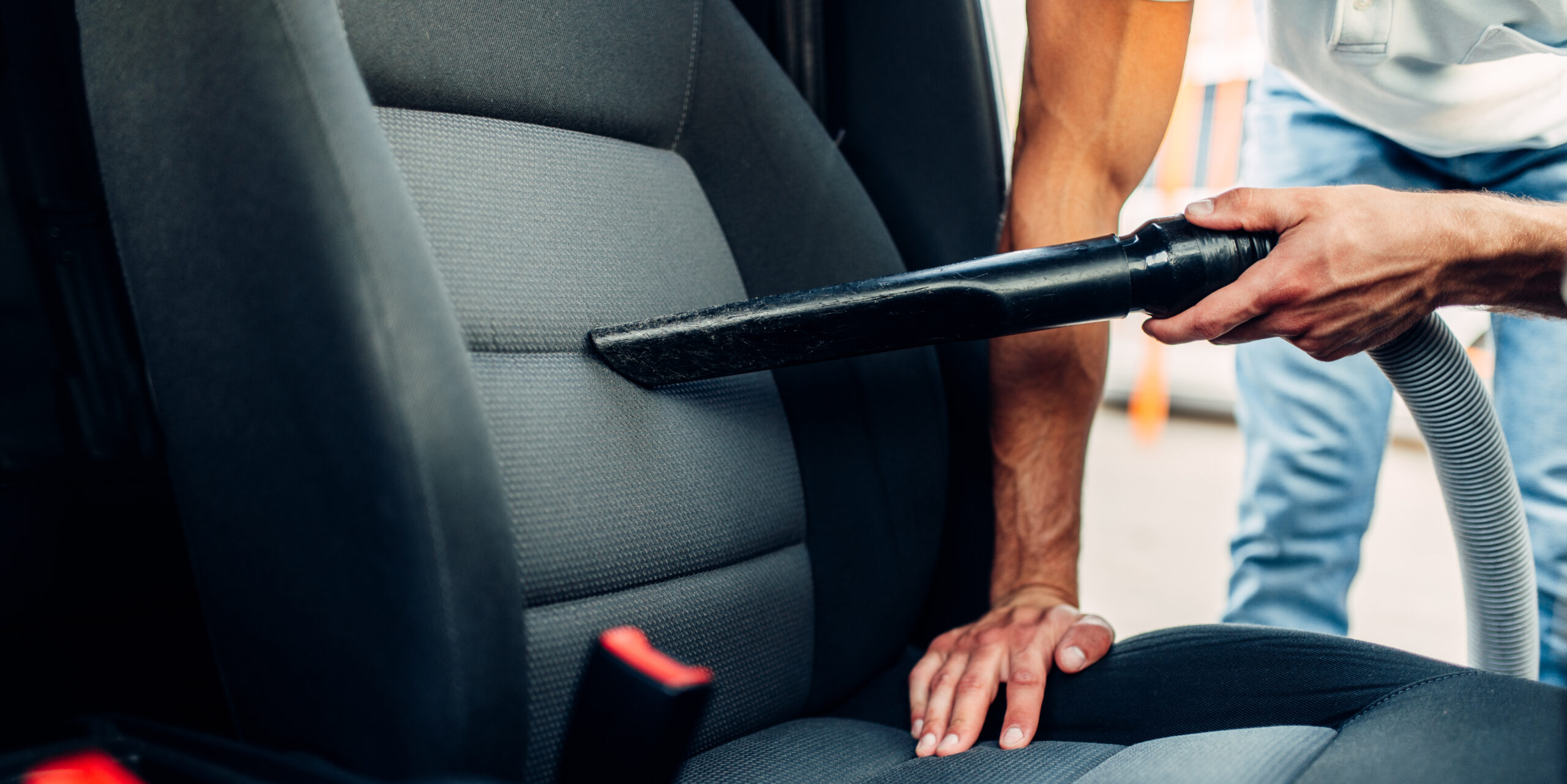 Un homme passe l'aspirateur dans une voiture dans une station de lavage de voiture Un homme passe l'aspirateur dans une voiture dans une station de lavage de voiture